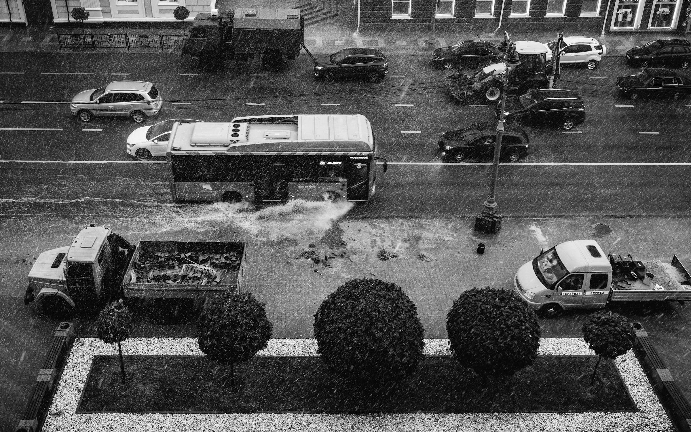 Cars and a bus pushing through a flooded city street