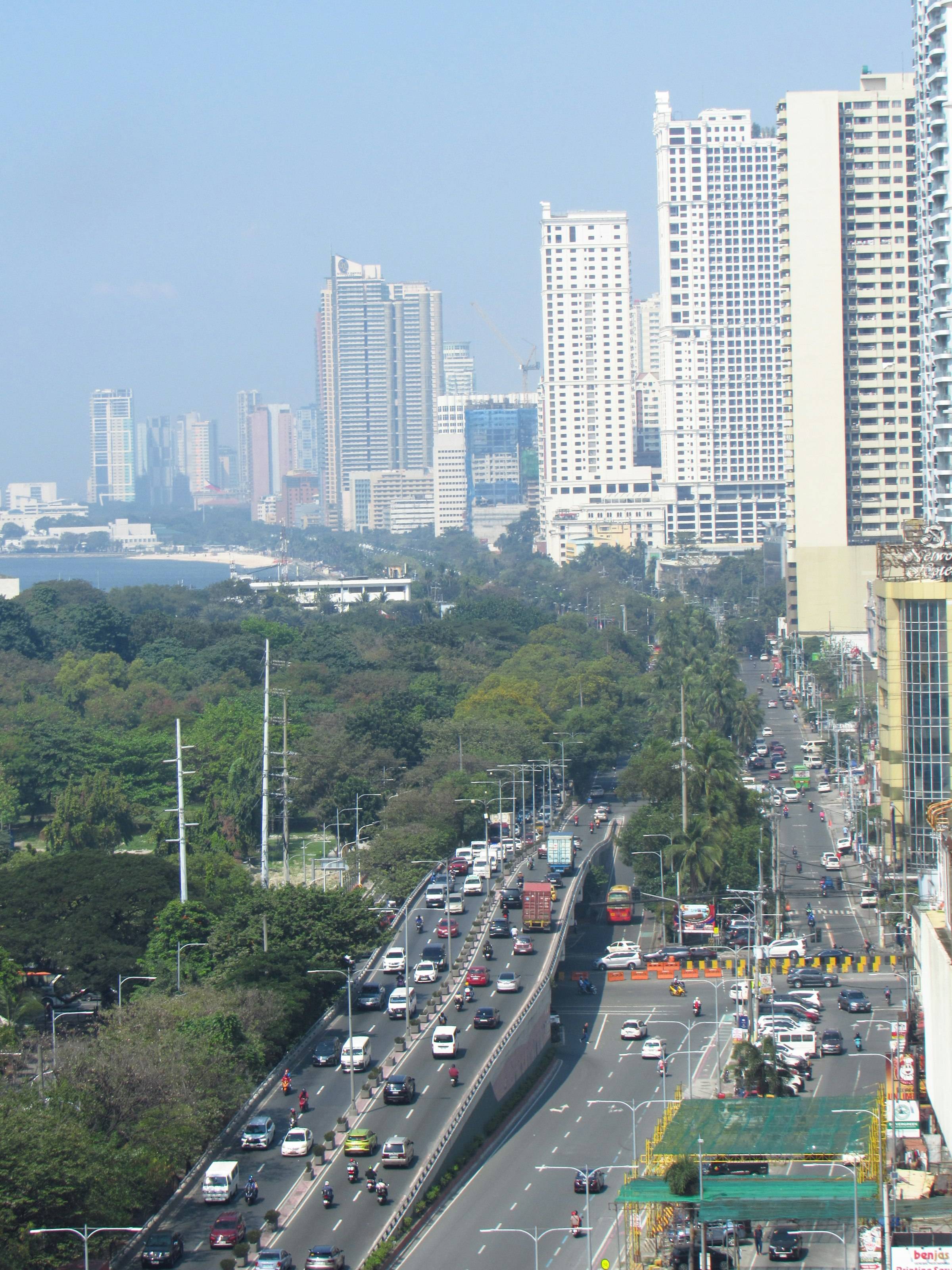 Metro Manila towers above a tree-lined highway