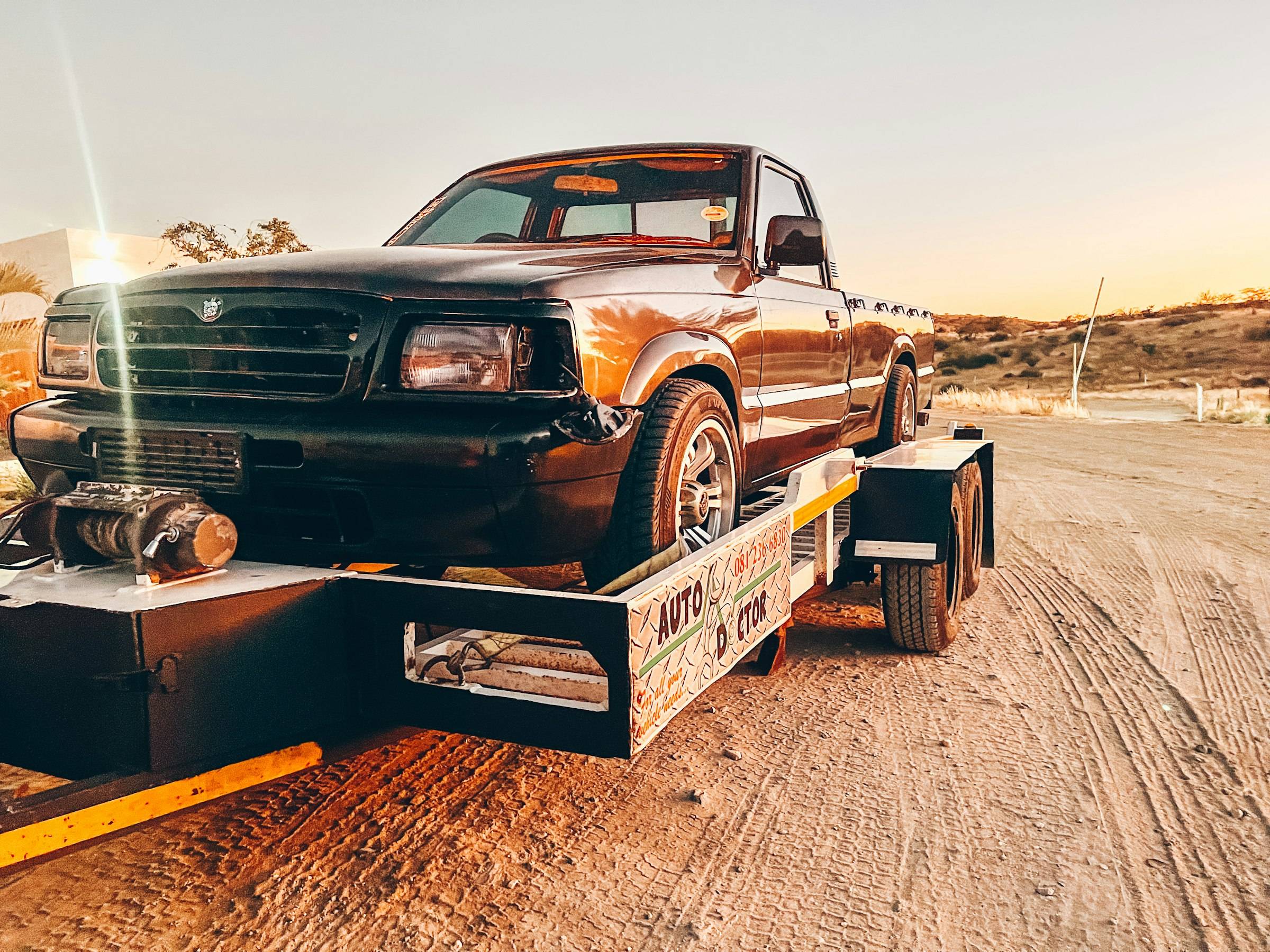 A pickup truck secured on a flatbed trailer in low evening light