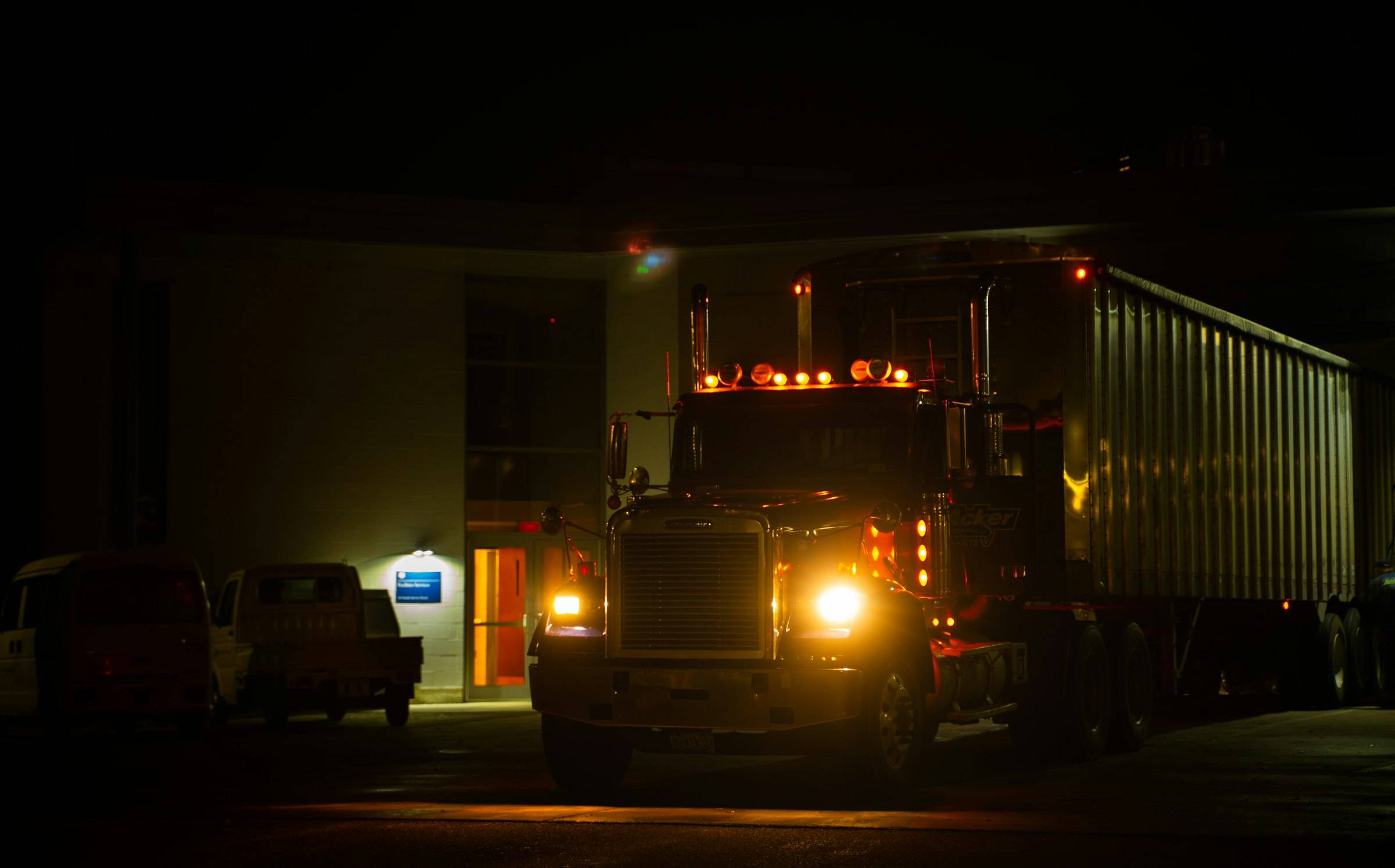A semi truck with its headlights on at night